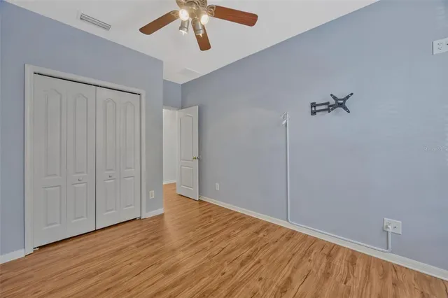 an empty room with wooden floor closet and windows