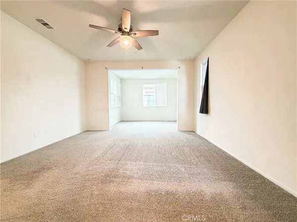 a view of a big room with a ceiling fan and window