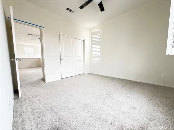 an empty room with a ceiling fan and a window