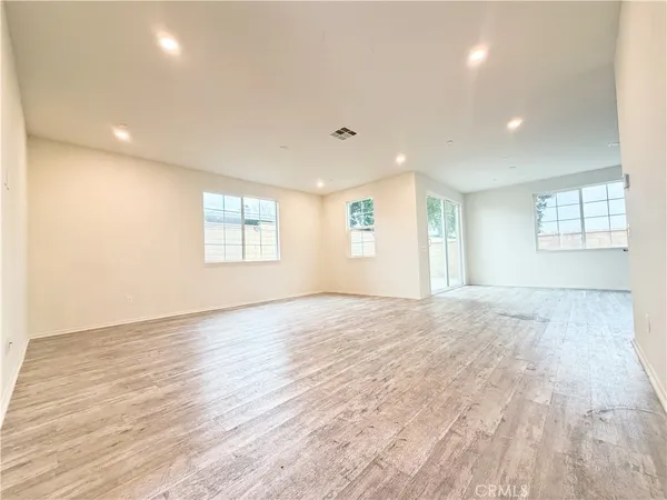 a view of an empty room with wooden floor and window