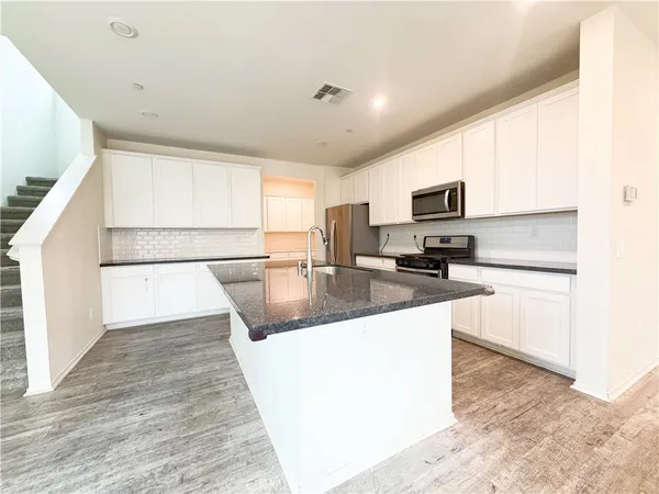 a large kitchen with kitchen island a stove a sink a refrigerator a window and cabinets