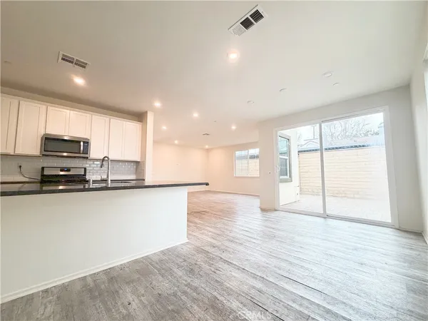 a large kitchen with stainless steel appliances granite countertop a stove a sink and a large window