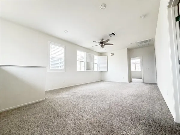 an empty room with windows and chandelier fan