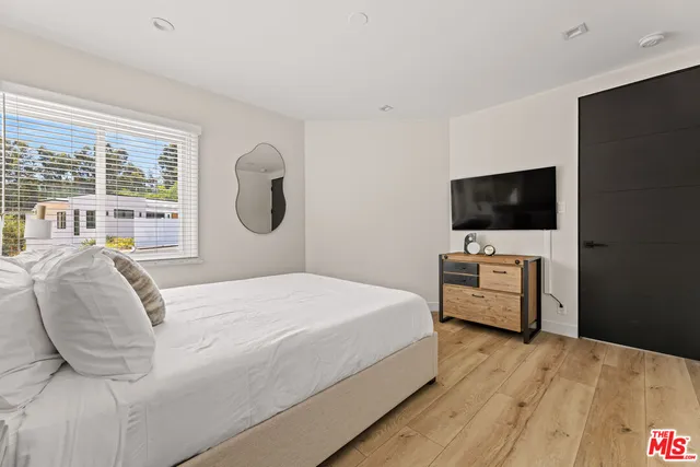 a bedroom with a bed and a flat tv screen on dresser