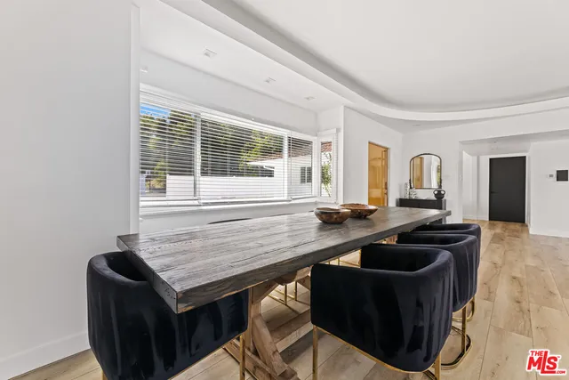 a dining room with wooden floor and windows