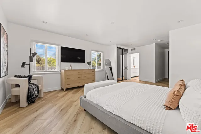 a bedroom with a bed and a flat tv screen on wall