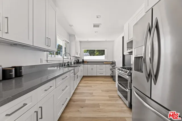 a large kitchen with stainless steel appliances granite countertop a refrigerator and a sink