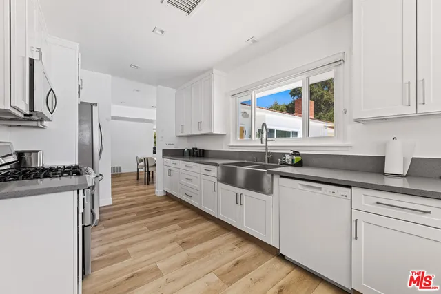 a large kitchen with stainless steel appliances granite countertop a stove a sink and white cabinets