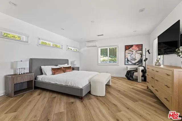 a bedroom with a bed and a flat tv screen on dresser