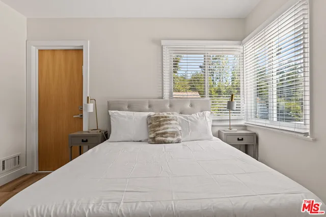 a bedroom with a large bed and two large window