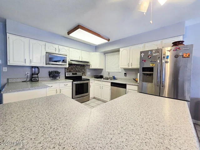 a kitchen with stainless steel appliances granite countertop a refrigerator sink and stove