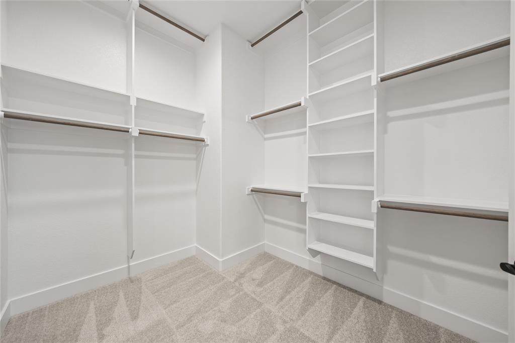 7004 Rnch Vw Place Springtown, TX 76082 - Photo 15 of 25 Walk-in closet featuring white built-in shelving, multiple hanging rods, and neutral-toned carpeting
