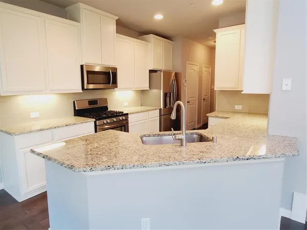 a kitchen with stainless steel appliances granite countertop a sink a stove top oven a counter space and cabinets