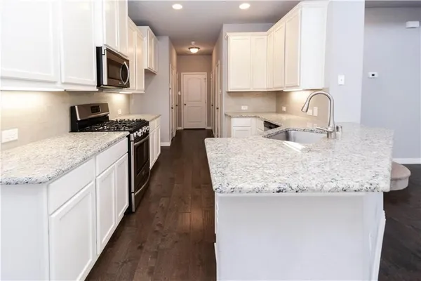 a large kitchen with granite countertop a sink and cabinets