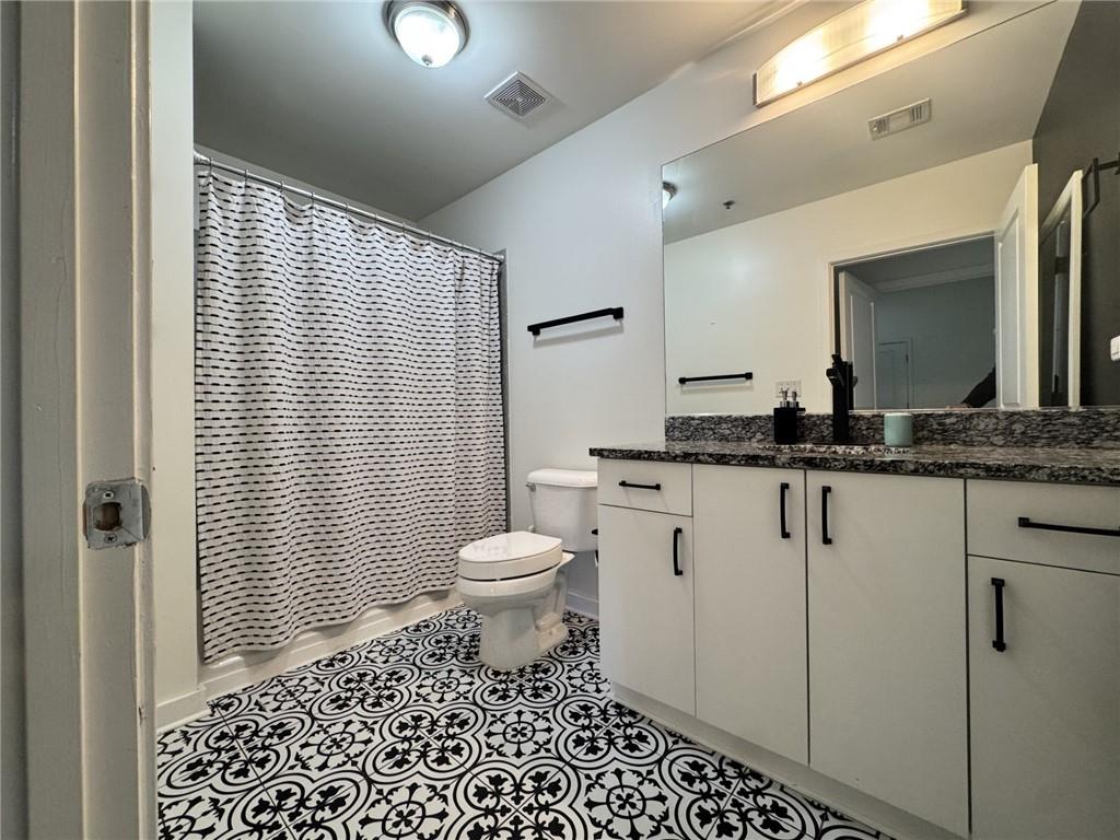 250 Pharr Road Northeast, Unit 601 Atlanta, GA 30305 - Photo 16 of 34 a bathroom with a granite countertop sink a toilet a mirror and shower