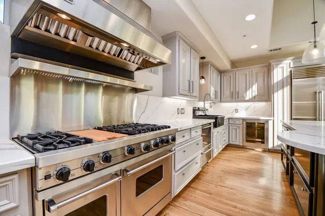 a kitchen with a stove a sink and wooden floor