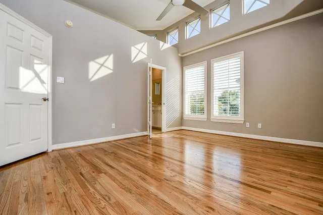 a view of an empty room with a window and wooden floor