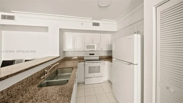 a kitchen with granite countertop a refrigerator sink stove and cabinets