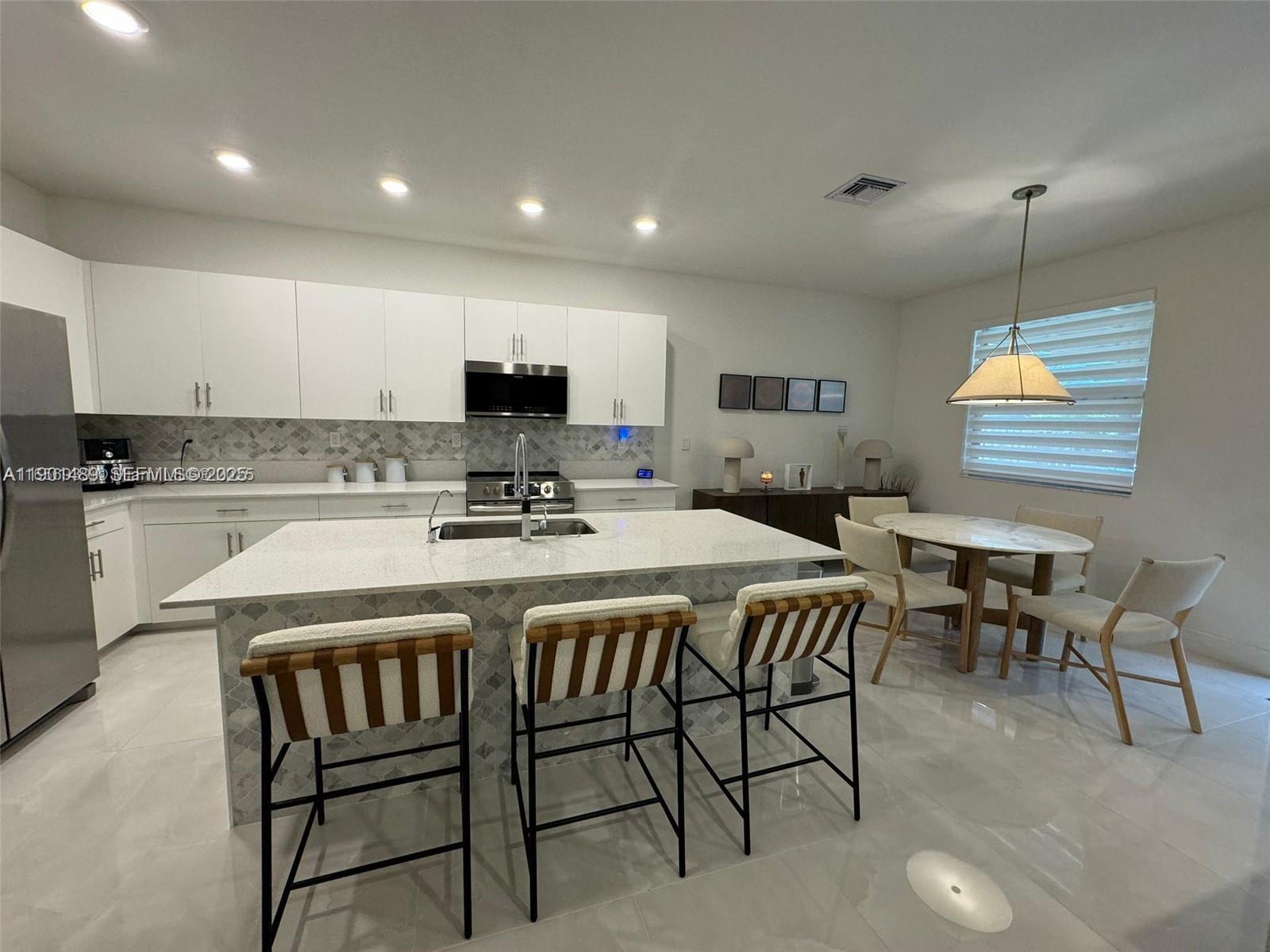 11910 Southwest 243rd Street Homestead, FL 33032 - Photo 12 of 24 a kitchen with a dining table chairs and white cabinets