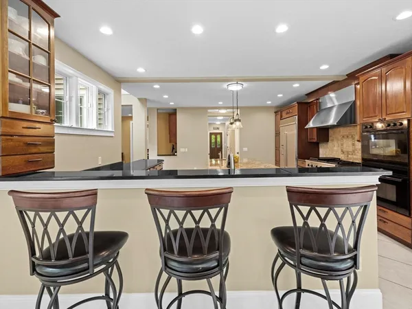 a kitchen with stainless steel appliances granite countertop a table chairs sink and cabinets