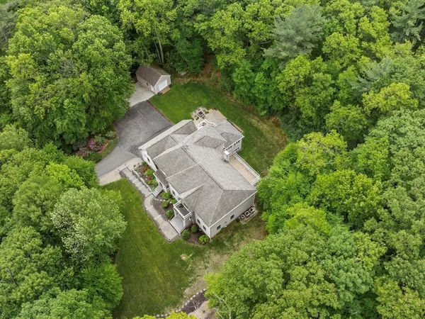 an aerial view of a house with a yard and large trees