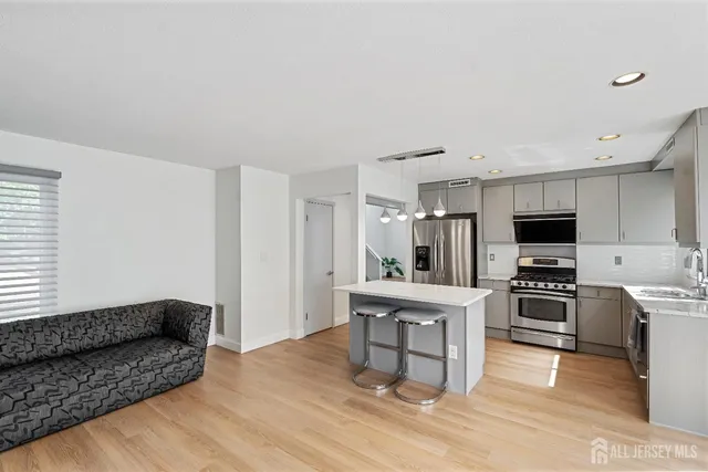 a living room with stainless steel appliances furniture and a kitchen view
