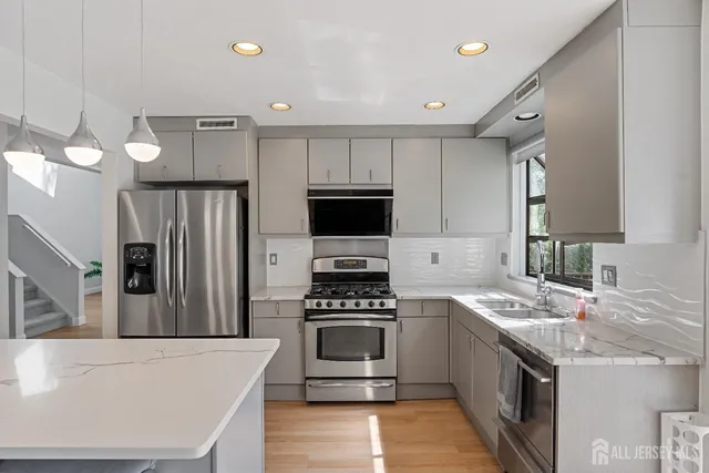 a kitchen with stainless steel appliances a stove a sink a microwave a refrigerator and cabinets