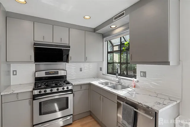 a kitchen with granite countertop a sink cabinets and stainless steel appliances