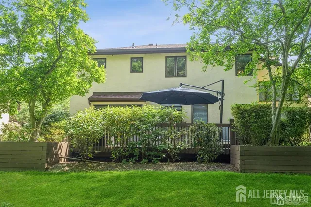 a view of a patio with table and chairs under an umbrella with wooden floor and fence