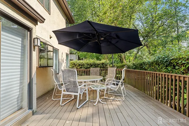 a view of a patio with table and chairs under an umbrella with wooden floor