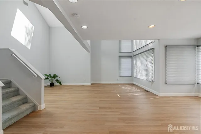 a view of an empty room with wooden floor and stairs