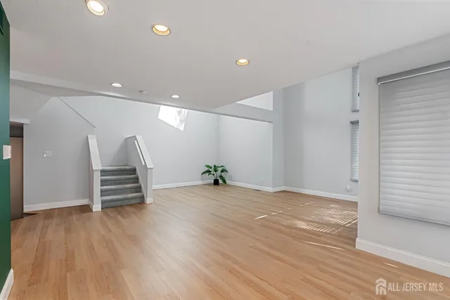 a view of an empty room with wooden floor and stairs