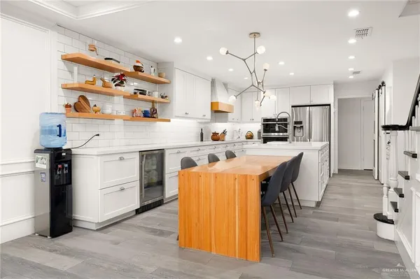 a kitchen with stainless steel appliances kitchen island granite countertop a table chairs refrigerator and microwave