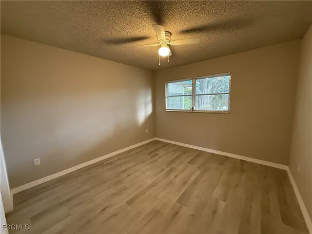 en empty room with windows and chandelier fan