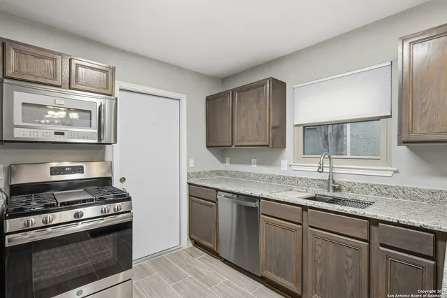 a kitchen with granite countertop cabinets stainless steel appliances and a sink