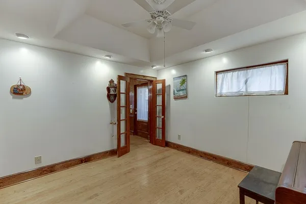 an empty room with wooden floor chandelier fan and windows