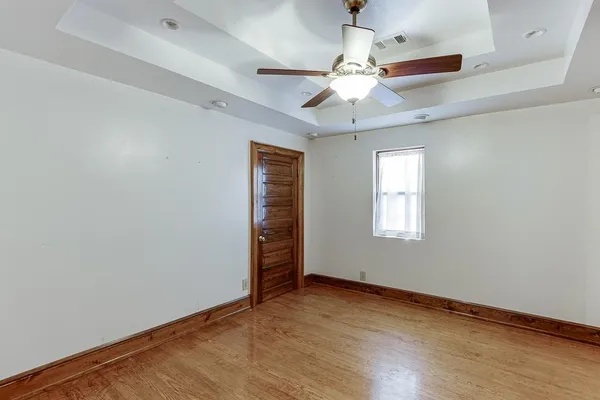 an empty room with ceiling fan and windows