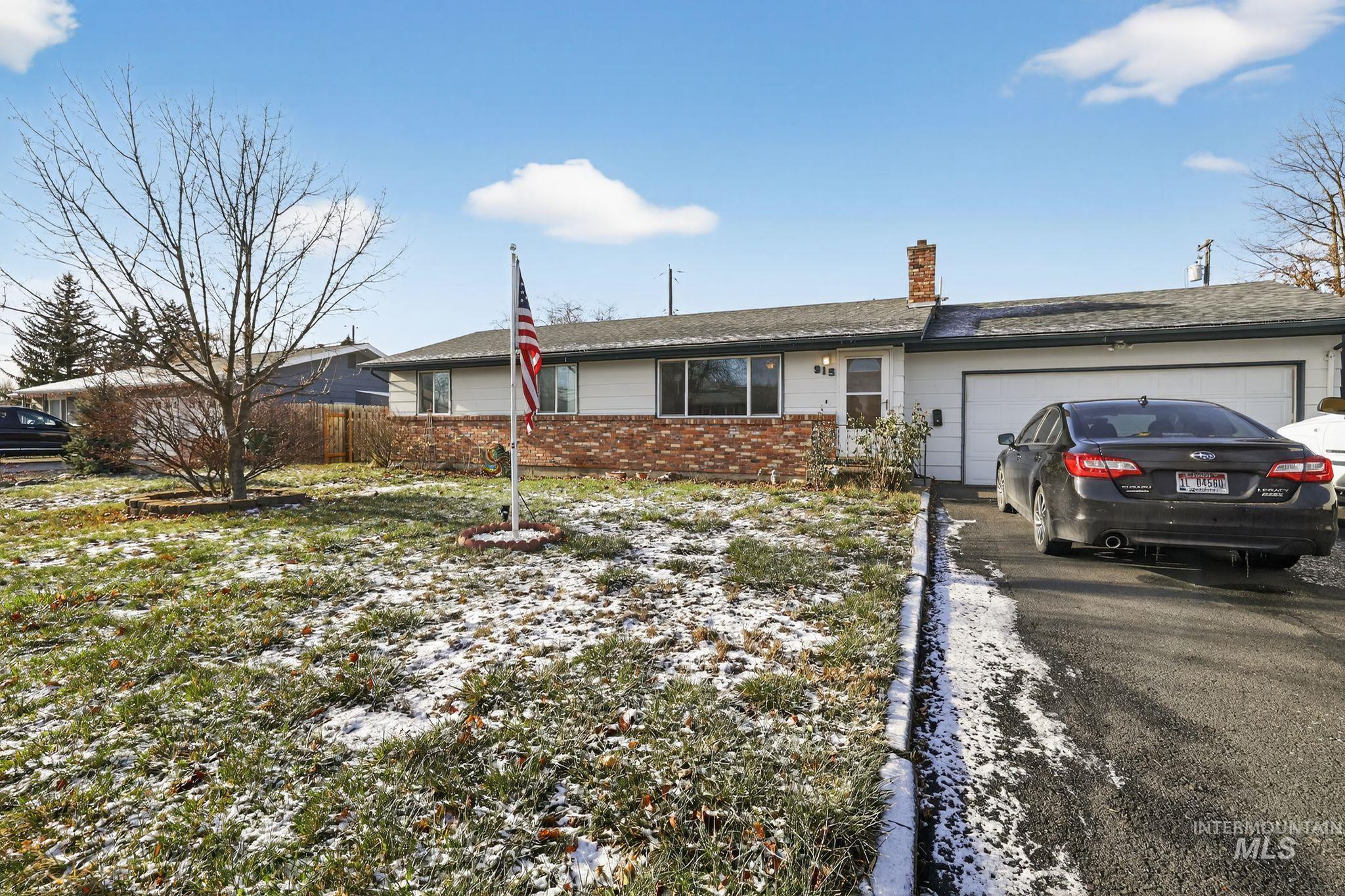 Single story home with a chimney, a garage, brick siding, and driveway