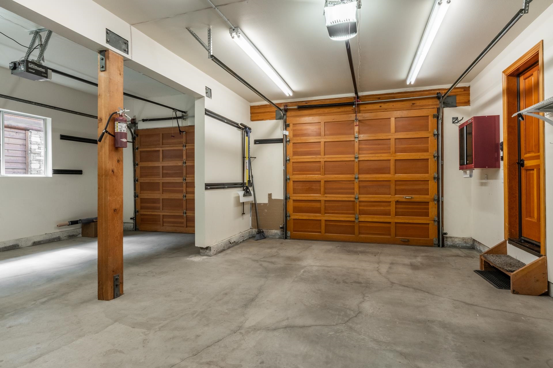 272 Ridge Way Mammoth Lakes, CA 93546 - Photo 45 of 55 Spacious garage featuring two wood-panel overhead doors with automatic openers, concrete flooring, and ample overhead fluorescent lighting