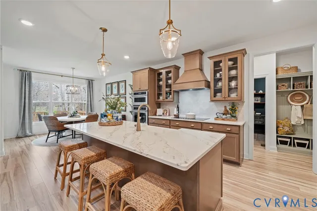 a large kitchen with granite countertop a stove a sink a dining table and chairs with wooden floor