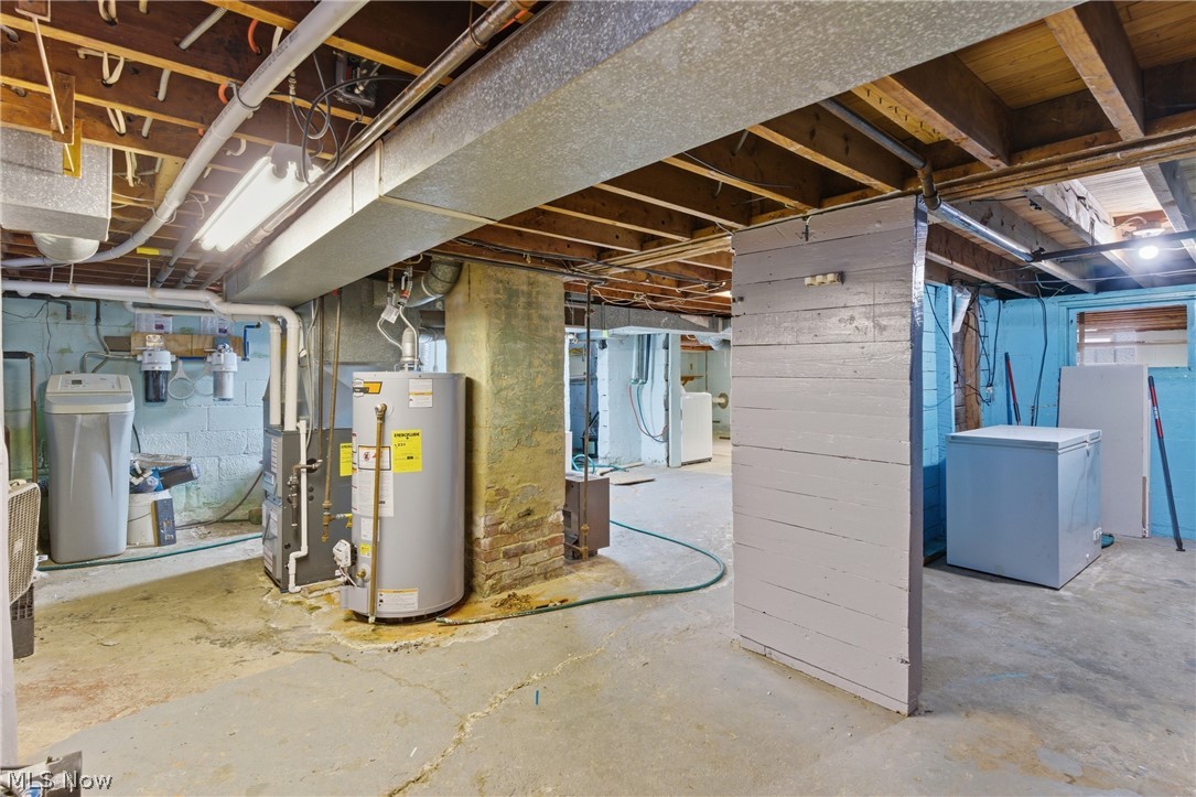 6291 Downs Road Northwest Warren, OH 44481 - Photo 24 of 44 Unfinished below grade area with white refrigerator, a water softener system, water heater, and heating unit