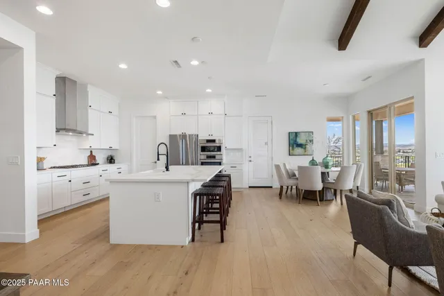 a large white kitchen with stainless steel appliances kitchen island granite countertop a large island in the center