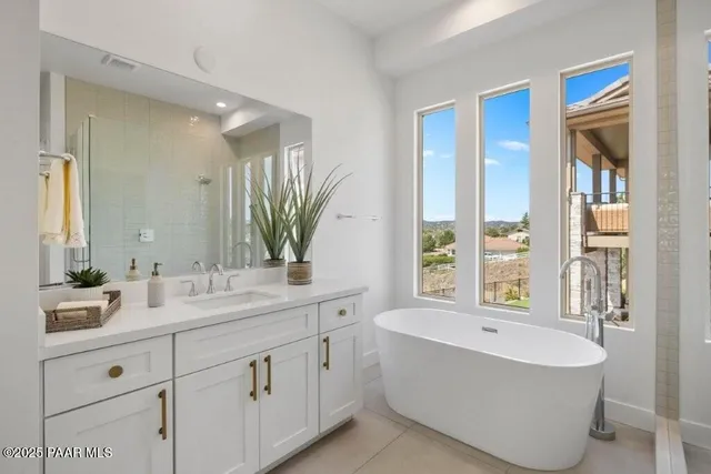 a spacious bathroom with a double vanity sink a mirror and a bathtub