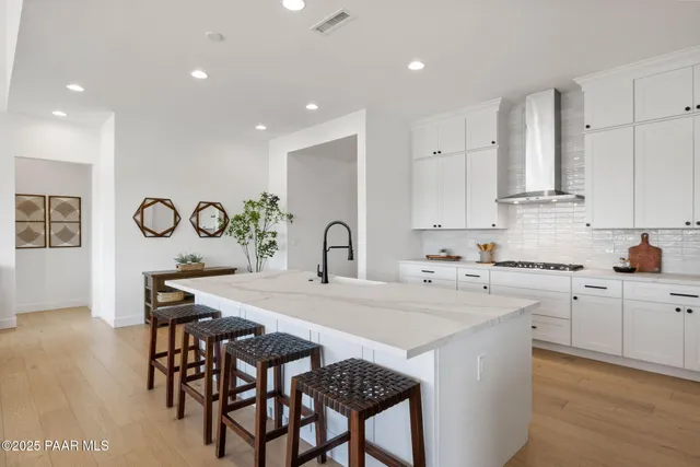 a kitchen with stainless steel appliances granite countertop a table chairs sink and cabinets