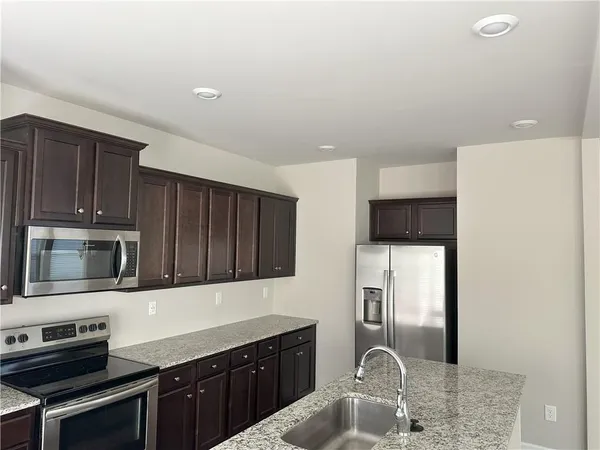 a kitchen with stainless steel appliances granite countertop a refrigerator stove and sink
