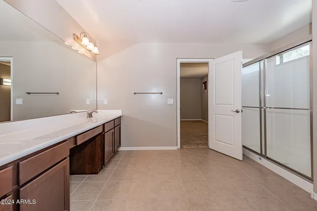 a spacious bathroom with a granite countertop sink a mirror and a shower