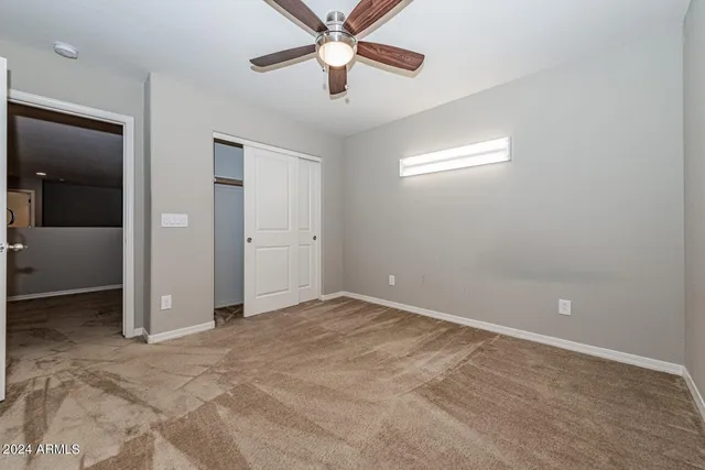 an empty room with closet and a chandelier fan