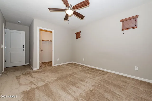 an empty room with closet and a ceiling fan
