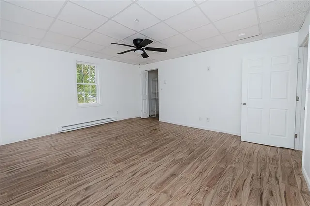 an empty room with wooden floor ceiling fan and windows