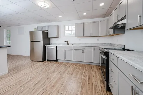 an empty room with wooden floor and windows